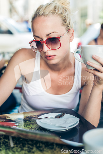Image of Woman drinking coffee outdoor on street.