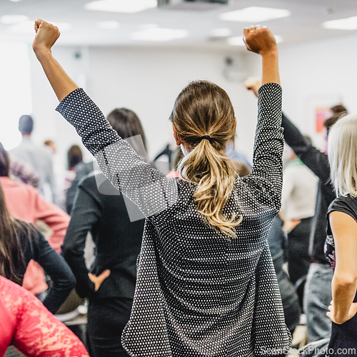 Image of Participants of interactive motivational speech feeling empowered and motivated, hands raised high in the air.