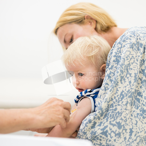 Image of Child beeing vaccinated by pediatrician in presence of his mother. Preventive vaccination against Diphtheria, whooping cough, tetanus, hepatitis, haemophilus influenzae, pneumococcus, poliomyelitis
