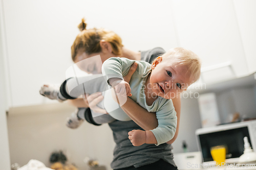 Image of That awkward moment when your mom sniffs your butt. Mother holding her baby, sniffing stinky diaper of her little boy checking if it is time to change it.