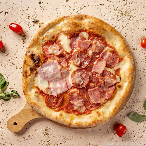 Image of Round, cooked pizza with pepperoni and ham