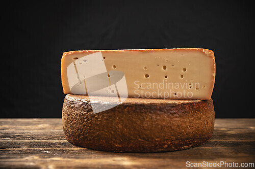 Image of Large piece of cheese with holes in it is sitting on top of anot