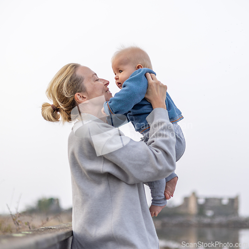 Image of Tender woman caressing her little baby boy infant child outdoors on autumn trip to Secovlje salinas landscape park, Slovenia. Mother's unconditional love for her child.