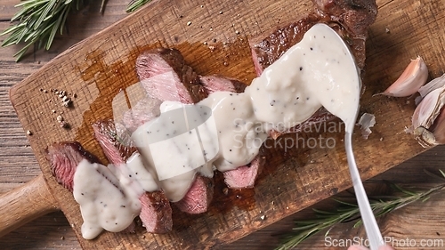Image of Chef pours pepper sauce on a slices of freshly grilled beef stea