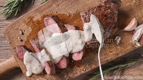 Image of Chef pours pepper sauce on a slices of freshly grilled beef stea
