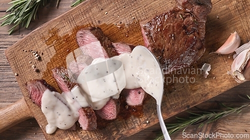 Image of Chef pours pepper sauce on a slices of freshly grilled beef stea