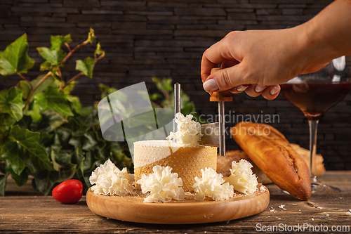 Image of Woman slicing delicious cheese