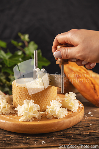 Image of Woman slicing cheese with girolle