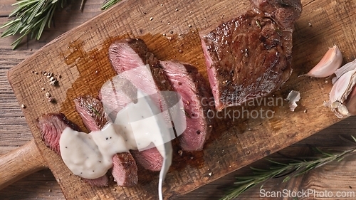 Image of Chef pours pepper sauce on a slices of freshly grilled beef stea