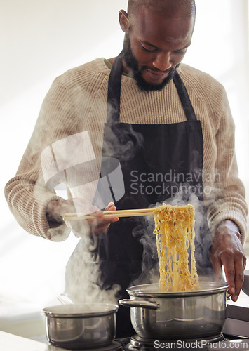 Image of Man, cooking noodles and pot with steam at home for lunch or dinner, busy and hungry for food with preparation. Catering, African chef with chopsticks for Asian cuisine and nutrition in kitchen