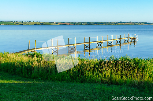 Image of Serene Wooden Dock Stretching Across Tranquil Waters at Sunrise 