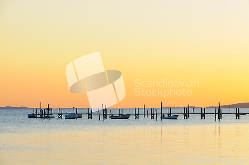 Image of Serene Sunset Over Tranquil Waters With Boats Docked at Rustic P