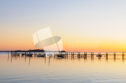 Image of Serene Sunset Over Tranquil Waters At A Wooden Dock On A Quiet E