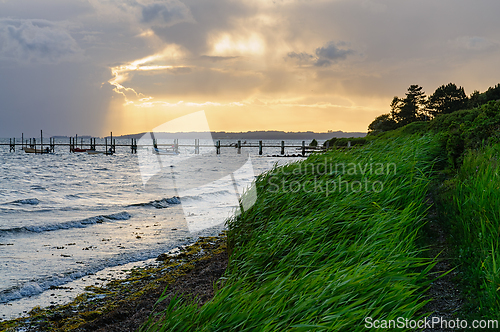 Image of Golden Rays Breaking Through Clouds Over Serene Waters at Dusk b