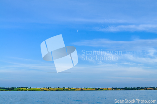 Image of Serene Morning Light Over Tranquil Waters With a Gentle Moon Han