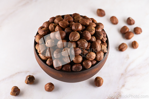 Image of Hazelnuts in a wooden bowl on marble countertop