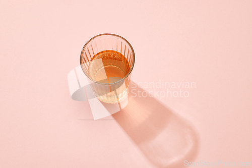 Image of glass of juice on pink background