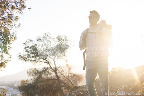 Image of Young father carrying his infant baby boy son in backpack while tracking around Malaga, Spain in sunset. Family travel and vacation concept