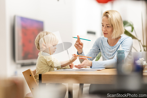 Image of Caring young Caucasian mother and small son drawing painting in notebook at home together. Loving mom or nanny having fun learning and playing with her little 1,5 year old infant baby boy child.