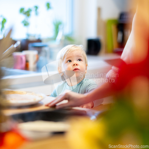 Image of Mother and little toddler baby boy making pancakes for breakfast together in domestic kitchen. Family, lifestyle, domestic life, food, healthy eating and people concept.