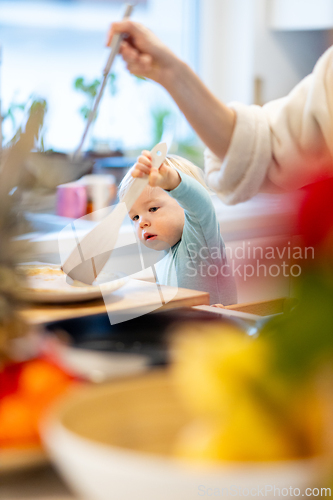 Image of Mother and little toddler baby boy making pancakes for breakfast together in domestic kitchen. Family, lifestyle, domestic life, food, healthy eating and people concept.
