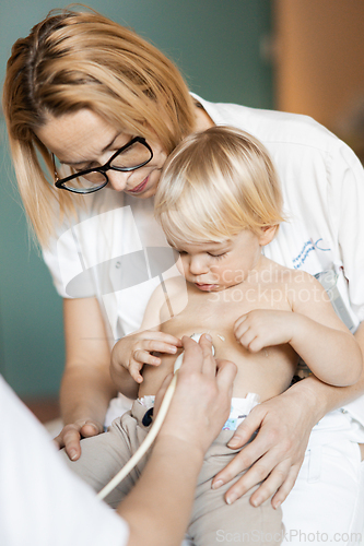 Image of Small child being checked for heart murmur by heart ultrasound exam by cardiologist as part of regular medical checkout at pediatrician.