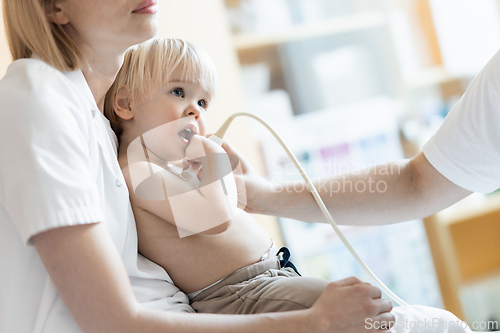 Image of Small child being checked for heart murmur by heart ultrasound exam by cardiologist as part of regular medical checkout at pediatrician.