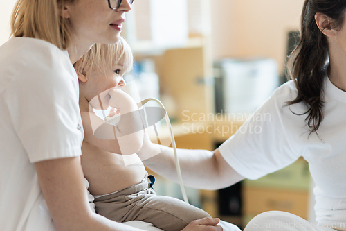 Image of Small child being checked for heart murmur by heart ultrasound exam by cardiologist as part of regular medical checkout at pediatrician.