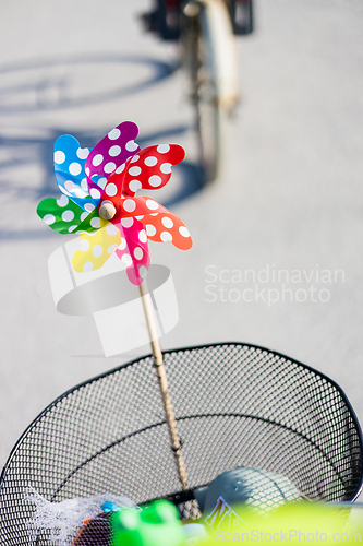 Image of Colorful pinwheel attached to bicycle basket to entertain toddler child riding on front child seat on bike in summer.