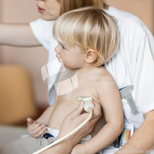 Image of Small child being checked for heart murmur by heart ultrasound exam by cardiologist as part of regular medical checkout at pediatrician.