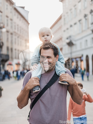 Image of Portrait of smiling father carrying his toddler child piggyback around city on family vacations. Happy father's day.
