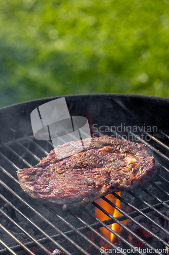 Image of steak grilling on charcoal grill