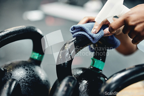 Image of Gym, cleaning or hand with sanitizer for kettlebell, safety or prevention or germs, virus and bacteria. Weights, spray or sports club janitor with dust cloth, liquid or hygiene of workout equipment