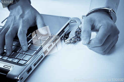 Image of  Handcuffed businessman on laptop