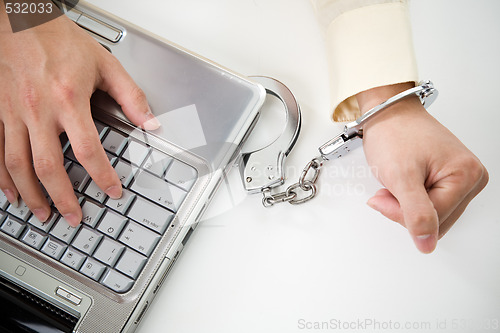 Image of  Handcuffed businessman on laptop