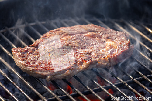 Image of steak grilling on charcoal grill