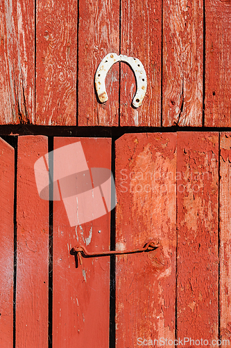 Image of A rustic wooden barn door adorned with a weathered horseshoe in 