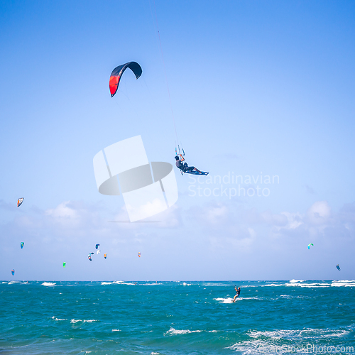 Image of Kiteboarding. Fun in the ocean. Extreme Sport Kitesurfing. Kitesurfer jumping high in the air performing triks during kitesurfing session.