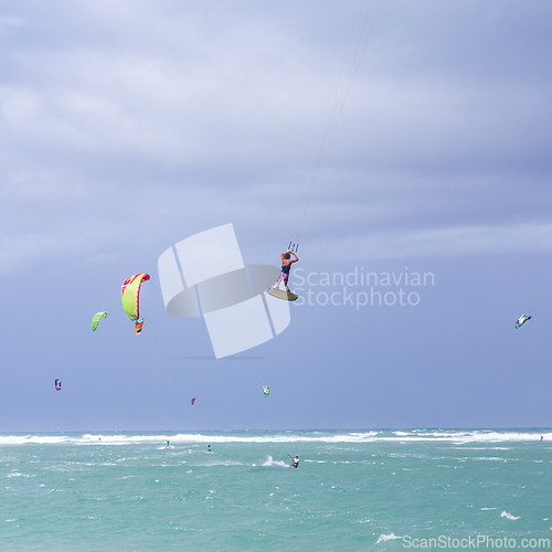 Image of Kiteboarding. Fun in the ocean. Extreme Sport Kitesurfing. Kitesurfer jumping high in the air performing triks during kitesurfing session.