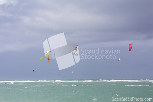 Image of Kiteboarding. Fun in the ocean. Extreme Sport Kitesurfing. Kitesurfer jumping high in the air performing triks during kitesurfing session.