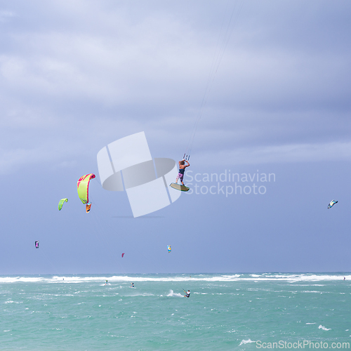 Image of Kiteboarding. Fun in the ocean. Extreme Sport Kitesurfing. Kitesurfer jumping high in the air performing triks during kitesurfing session.
