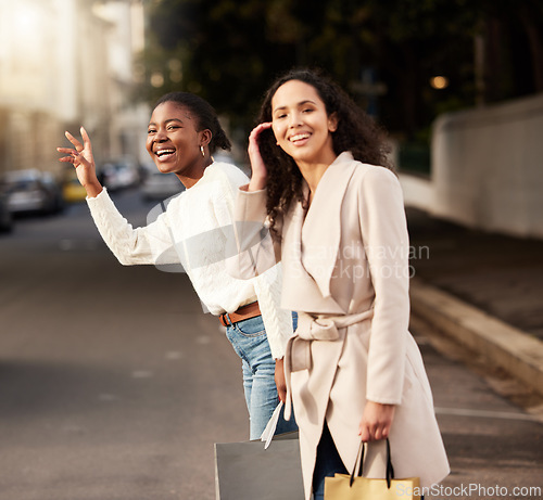 Image of Women, city and calling for taxi after shopping with smile, happiness with sale on product. Female friends, together and hand sign with fashion in urban for car, transport or travel from sidewalk