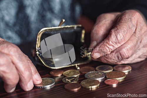 Image of Detailed closeup photo of elderly 96 years old womans hands counting remaining coins from pension in her wallet after paying bills. Unsustainability of social transfers and pension system.
