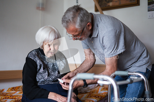 Image of Man is helping an elderly woman with everyday tasks, helping with technology, setting video face time with her family using smart phone.