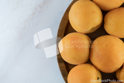 Image of Ripe apricots on a wooden plate, top view