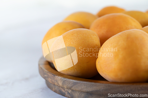 Image of Ripe apricots on a wooden plate, close-up