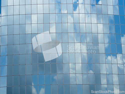 Image of Blue sky with clouds reflected in glass windows of skyscraper