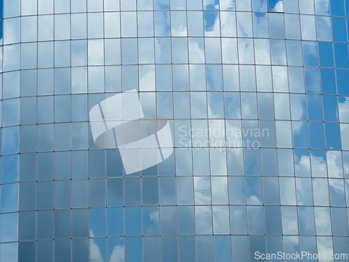 Image of Blue sky with clouds reflected in glass windows of skyscraper