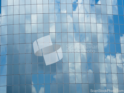 Image of Blue sky with clouds reflected in glass windows of skyscraper