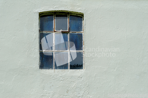 Image of A weathered window frame reveals glimpses of nature outside on a